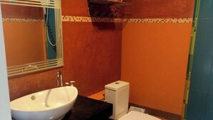 Une salle de bain avec un lavabo blanc, des toilettes et un miroir.