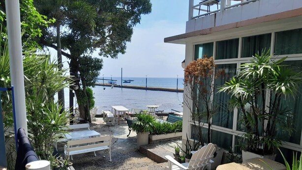 Un espace patio aménagé avec du mobilier d’extérieur, des plantes en pot et une vue sur la mer.