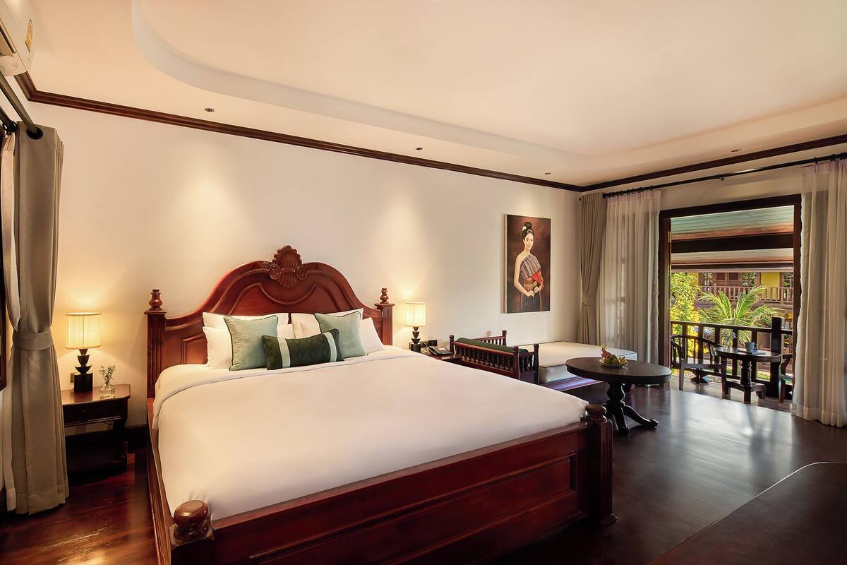 Amplia habitación de hotel con una cama grande, una mesita y un balcón con vistas.
