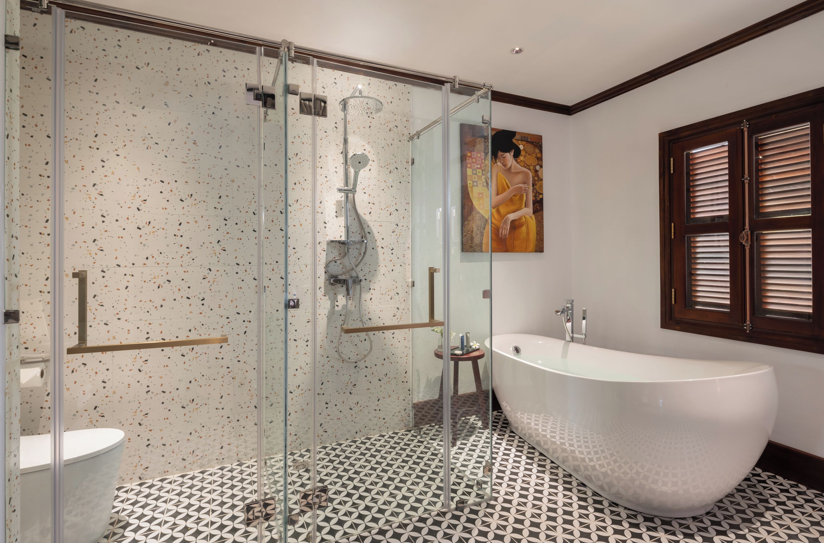 Ein modernes Badezimmer mit freistehender Badewanne, einer gläsernen Dusche und einem gemusterten Boden.