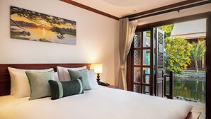 Une chambre d’hôtel avec un grand lit, un tableau représentant un coucher de soleil, une vue sur un jardin et un balcon donnant sur un bassin.