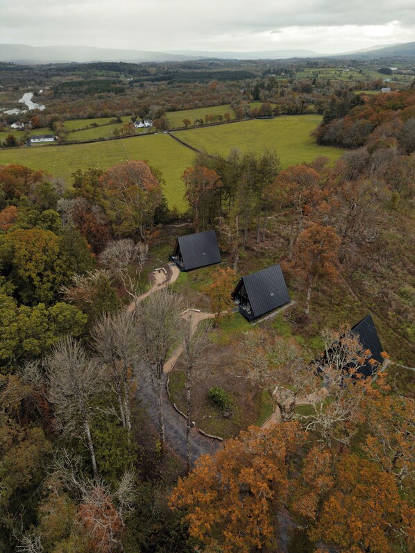 An aerial view of a rural landscape with two cabins surrounded by trees and fields. - Drumhierny Woodland Hideaway (Carrick-on-Shannon)