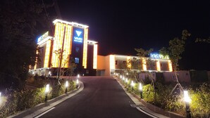 A building with illuminated signage, a well-lit entrance, and a pathway leading to the entrance. - VIVID (Muan)