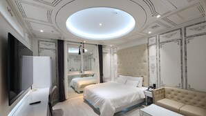 A modern hotel room with a large bed, a sofa, a TV, and a mirror. - VIVID (Muan)