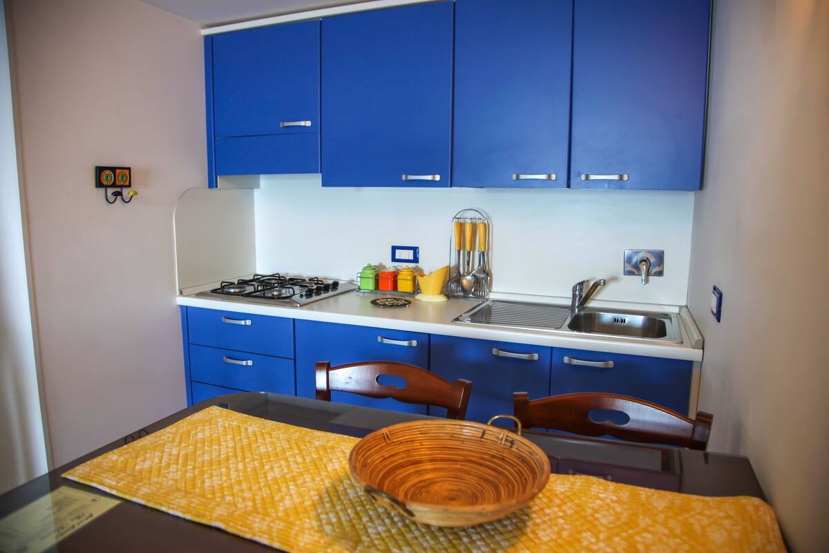 A compact kitchen with blue cabinets, a gas stove, and a sink.