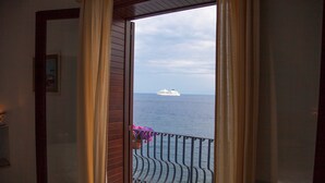 Un balcón con vista al mar y un crucero a lo lejos.