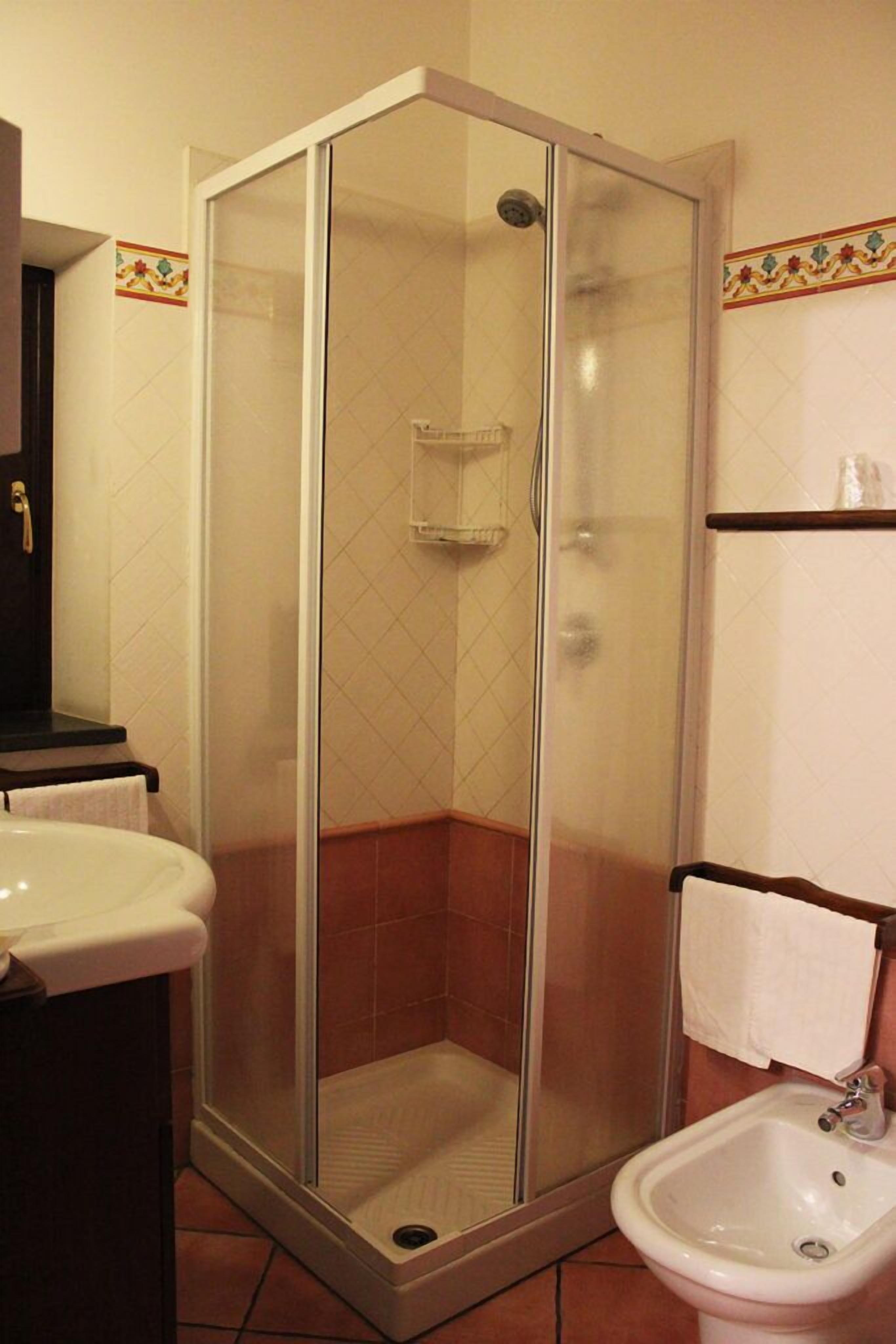A bathroom with a glass-enclosed shower, a sink, and a toilet.