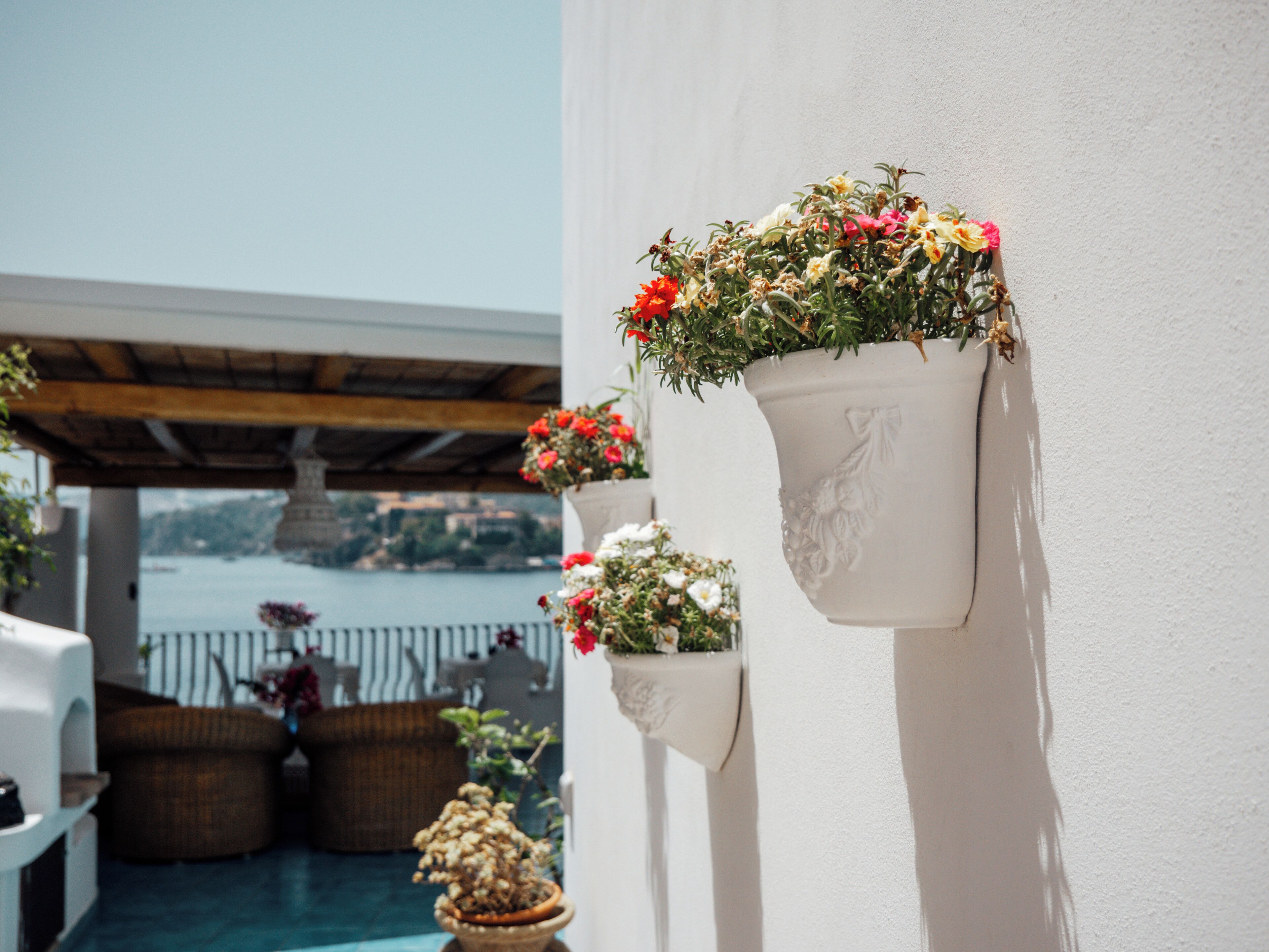 A balcony with potted plants and a view of the sea.