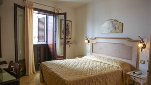 Un dormitorio con una cama grande, una mesita de noche, una silla y una puerta con cortina.