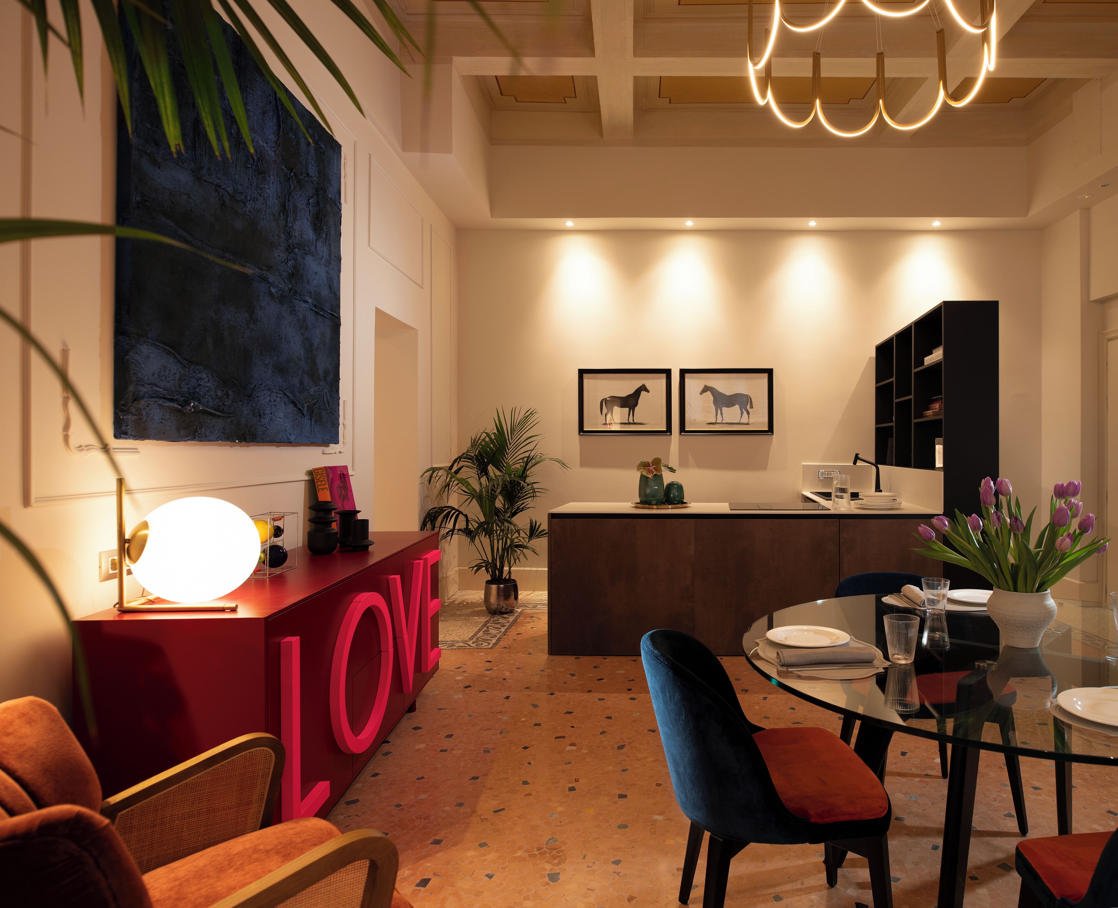 Een modern interieur met een bar in LOVE-thema in het rood, een eetgedeelte met een glazen tafel, en een keuken op de achtergrond.