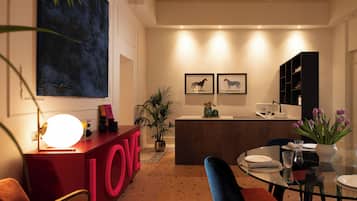 Een modern interieur met een bar in LOVE-thema in het rood, een eetgedeelte met een glazen tafel, en een keuken op de achtergrond.