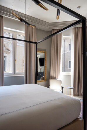 Ein geräumiges Schlafzimmer mit einem großen Bett, einem Sessel, einem kleinen Tisch und einem Spiegel.