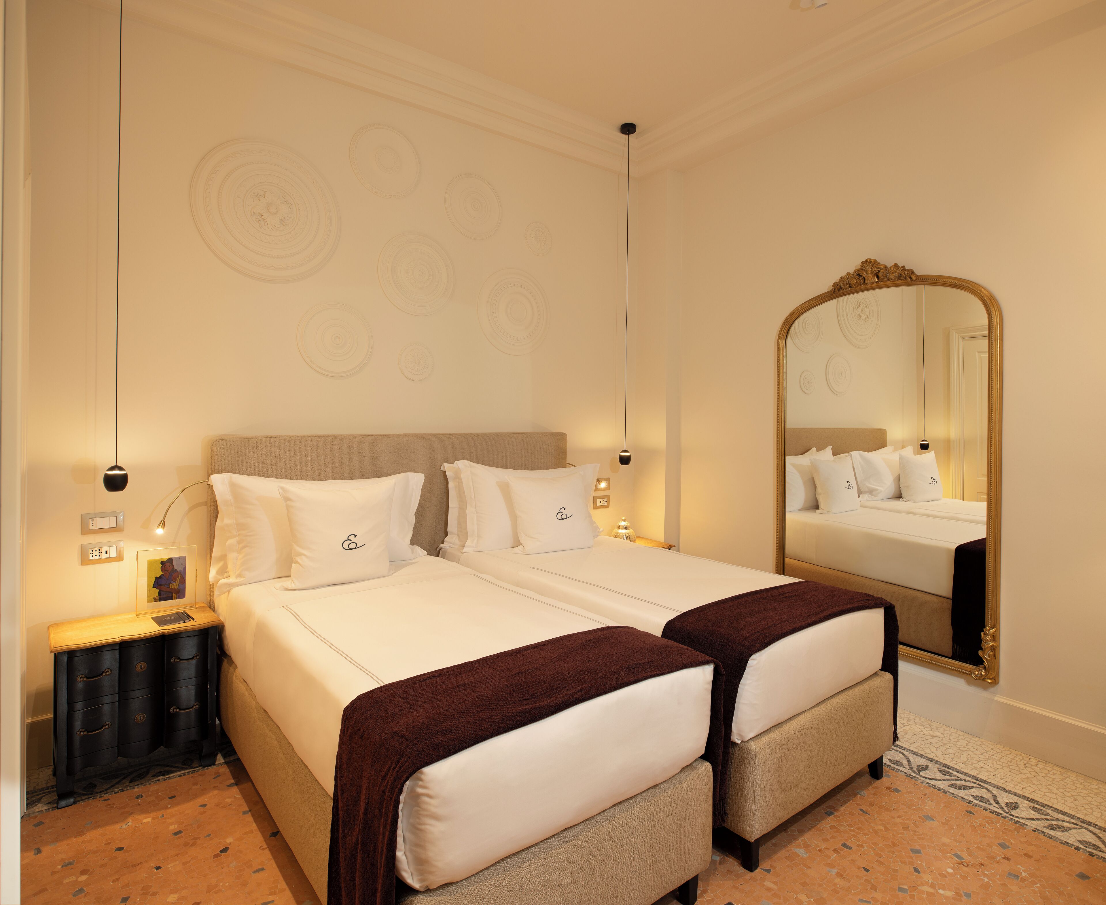 Ein Hotelzimmer mit einem großen Bett, einem Nachttisch, einem Spiegel und einer Wand mit kreisförmigen Mustern.