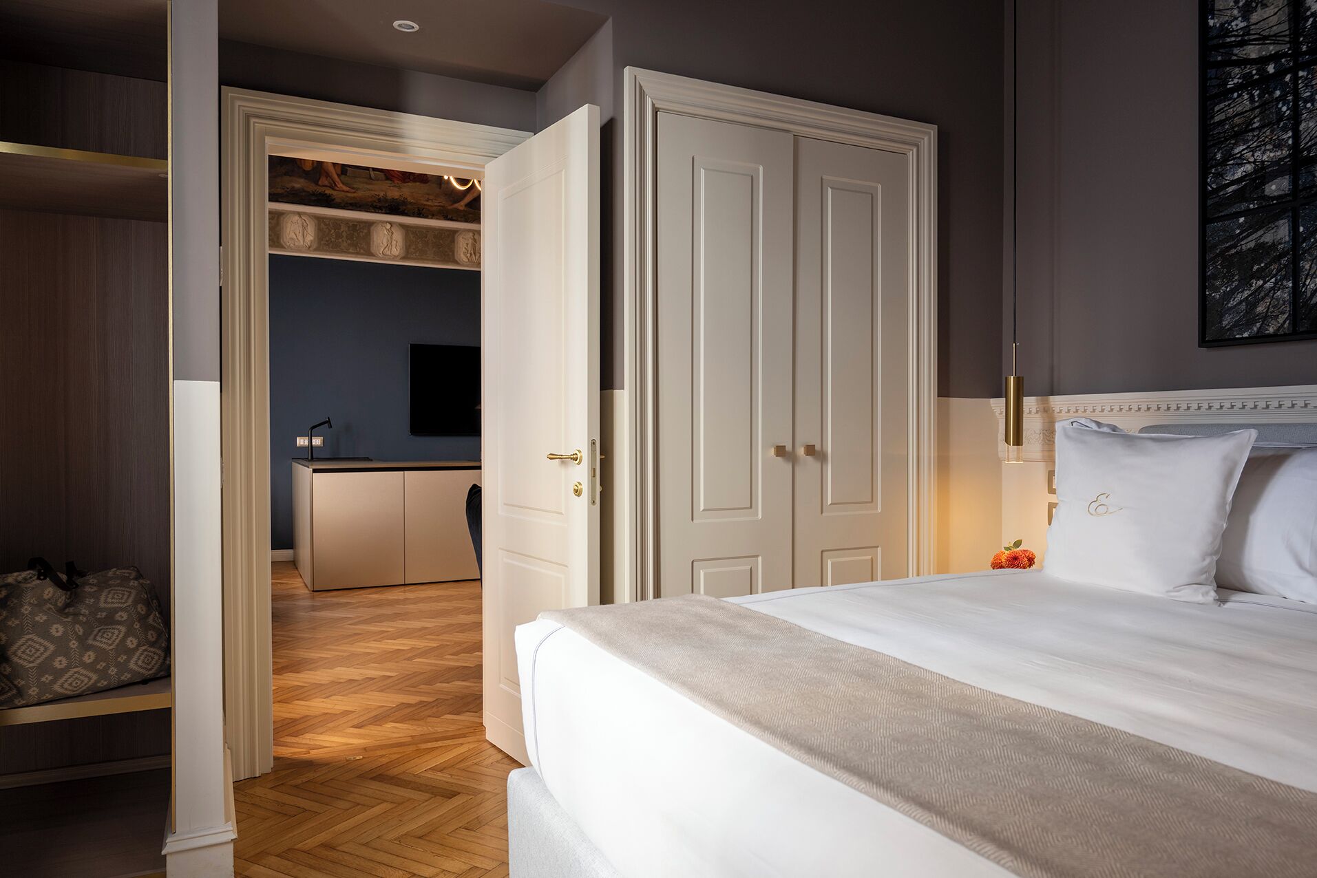 A bedroom with a large bed, a wardrobe, and a desk area with a chair.