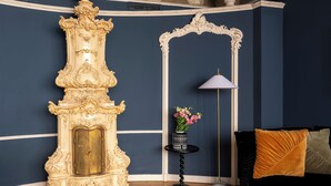 Una stanza con un grande armadio dorato e decorato, un arco bianco decorativo, una lampada da terra e un divano nero con un cuscino.