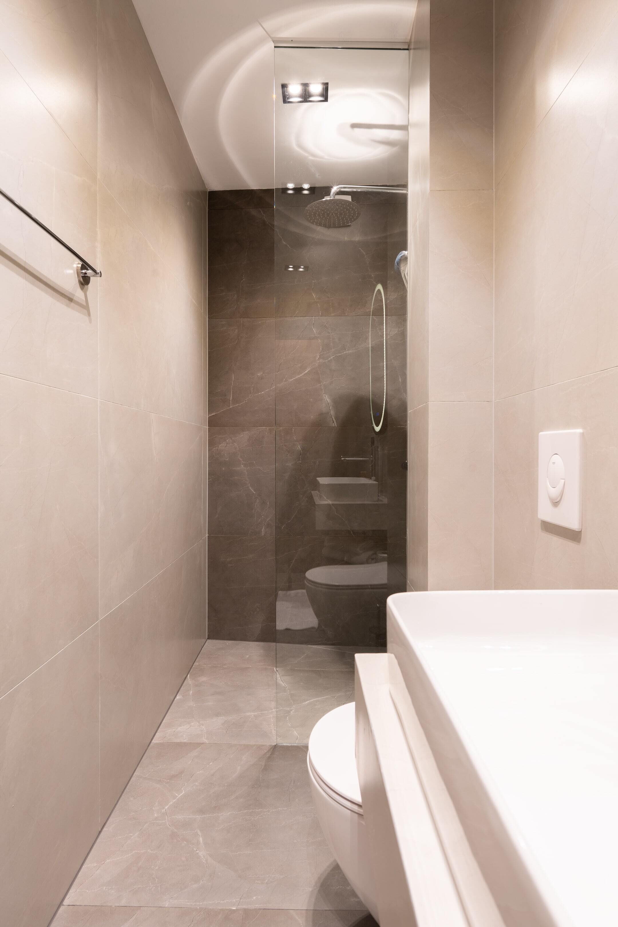A modern bathroom with a glass-enclosed shower, a toilet, and a vanity with a mirror.