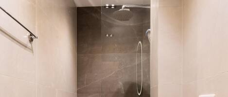 A modern bathroom with a glass-enclosed shower, a toilet, and a vanity with a mirror.