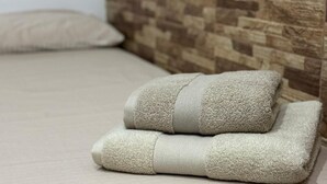 A bed with a wooden headboard and two folded towels. - Apartamento Caleta Beach (Cádiz)