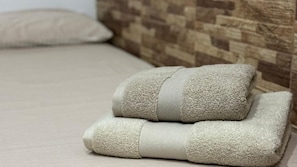 A bed with a wooden headboard and two folded towels.