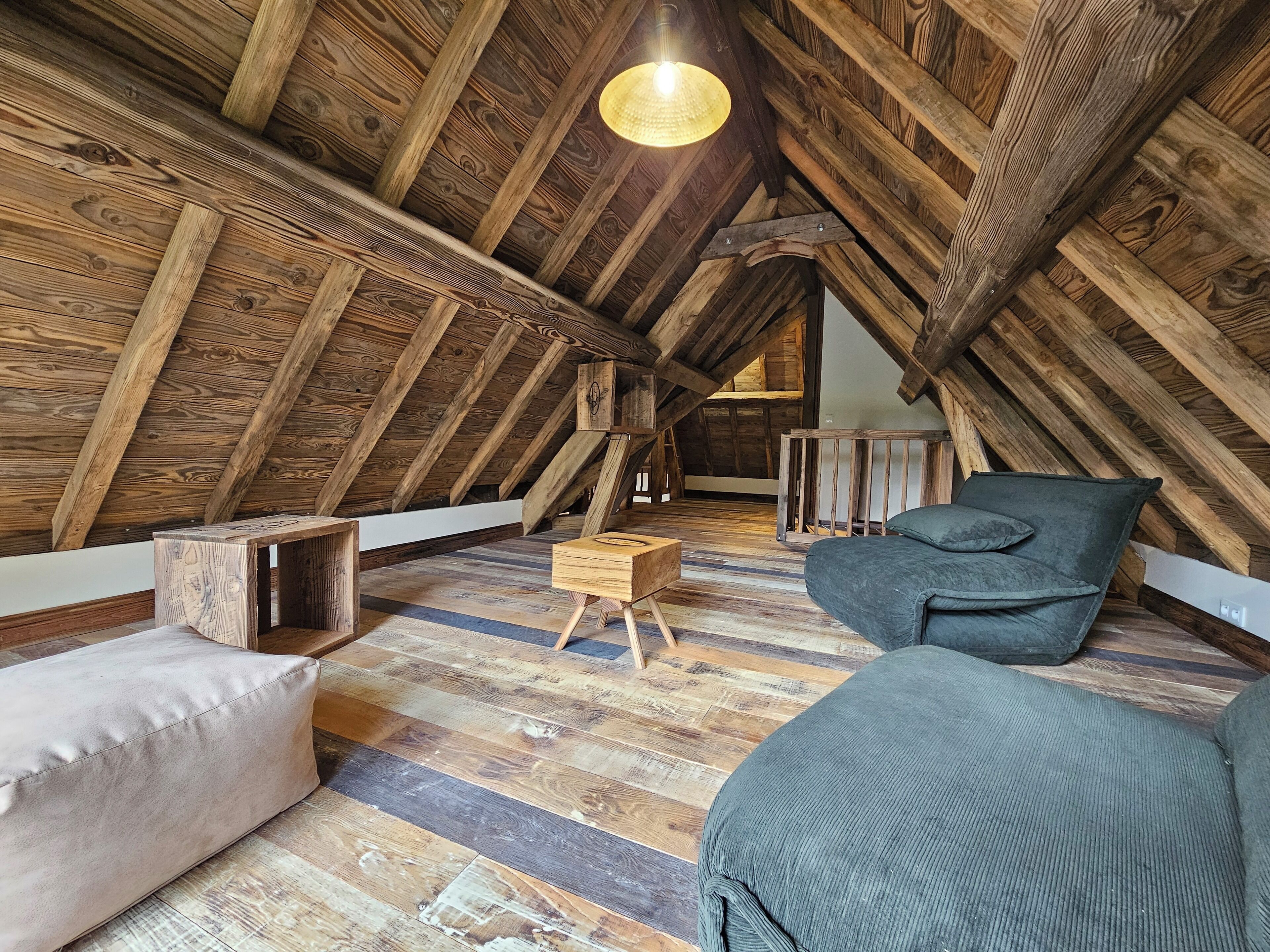 Habitación de ático con vigas de madera a la vista, techo inclinado y estética rústica.