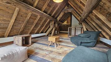 Habitación de ático con vigas de madera a la vista, techo inclinado y estética rústica.
