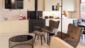 Een moderne keuken met een inbouwfornuis, een flatscreen televisie en een eethoek met een bank en stoelen.
