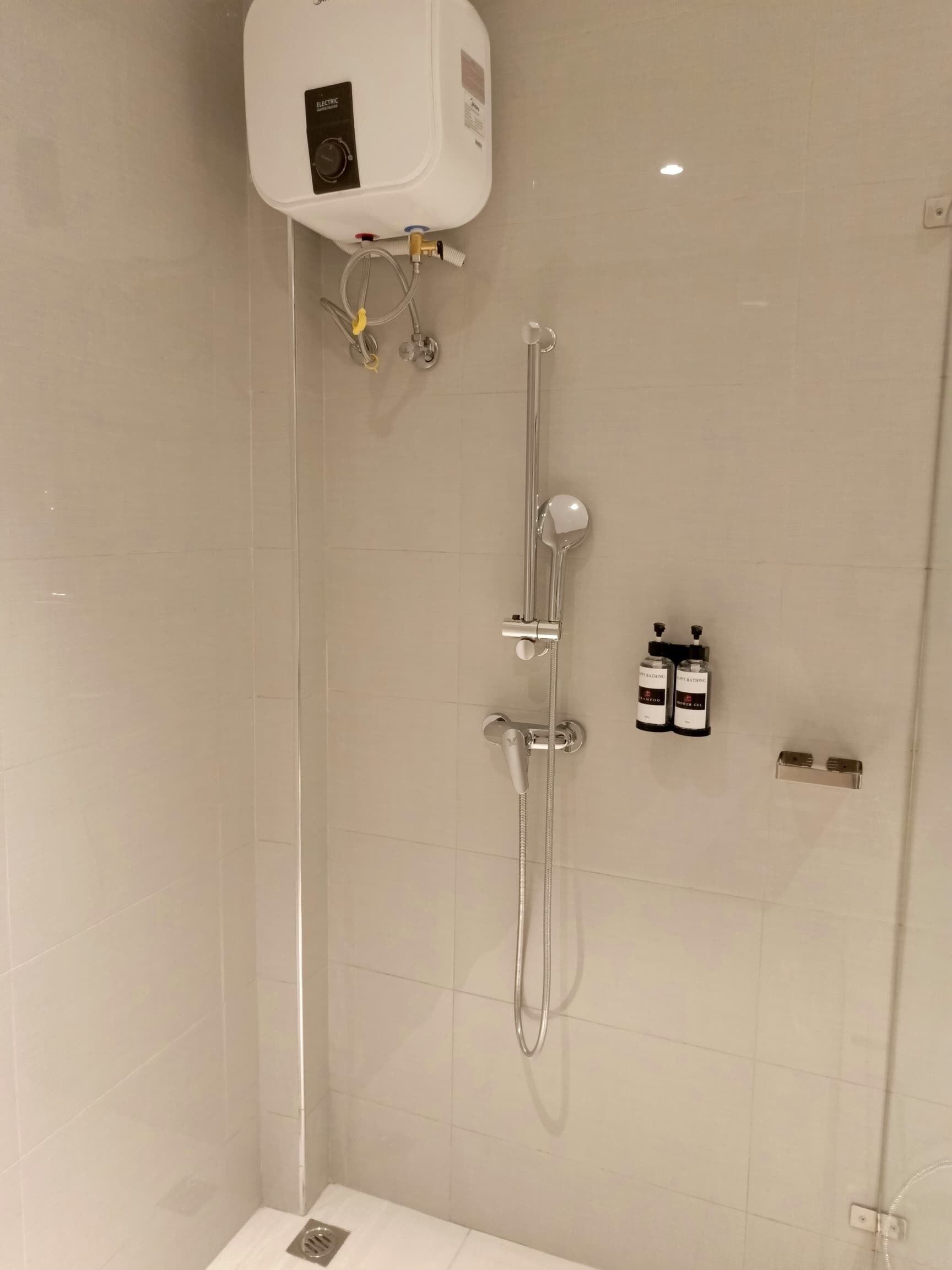 Ein modernes Duschbad mit integriertem Boiler, einer Handbrause und zwei Shampoo-Flaschen.