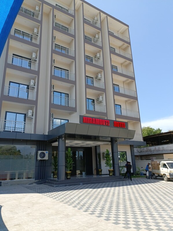 Um hotel com vários andares e design moderno, com varandas e aparelhos de ar condicionado em cada pavimento.