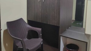A room with a wardrobe, a chair, a small table, and a trash bin. - Hotel Route 55 (Darjeeling)
