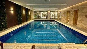 Piscina interior moderna con vistas despejadas a los vestuarios y un área de descanso con asientos acolchados.