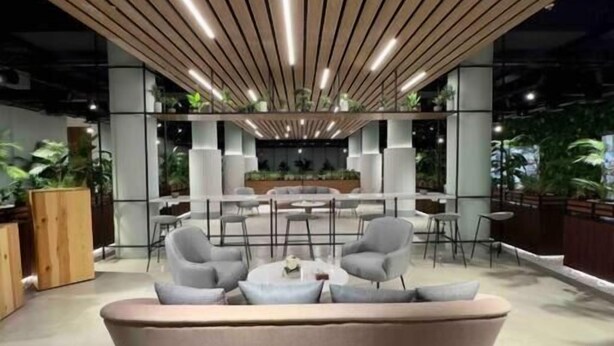 Un espacio lounge moderno con un sofá curvo, sillas grises y una mesa central.