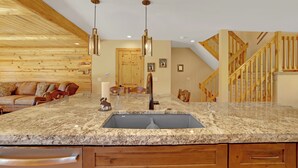 Una cocina con encimera de granito, pileta de acero inoxidable y muebles de madera.