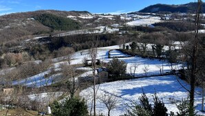 Paisaje rural con campos nevados, un camino sinuoso y un pequeño edificio en primer plano.