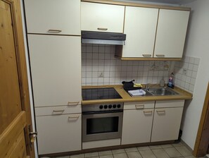 A compact kitchen with white cabinets, a black range hood, a stainless steel oven, and a sink with a dish soap bottle. - Accommodations in downtown Schwabach for 2 people (Schwabach)