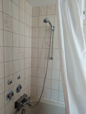 A bathroom with a shower, tiled walls, and a curtain.