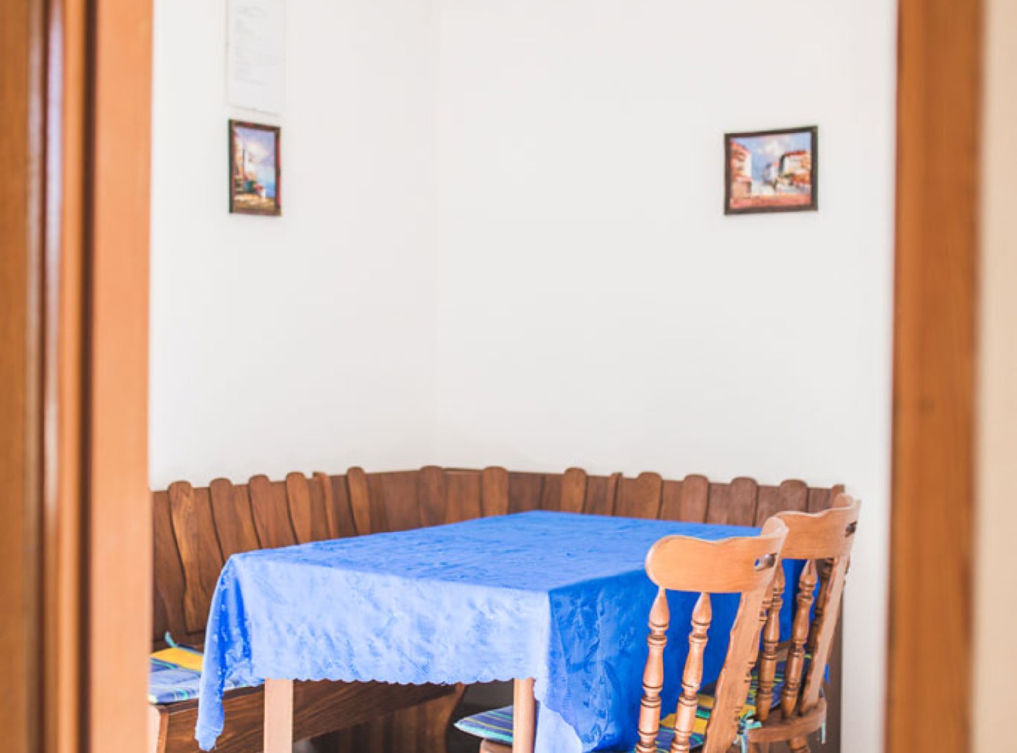 A dining area with a wooden bench and a table covered with a blue tablecloth.