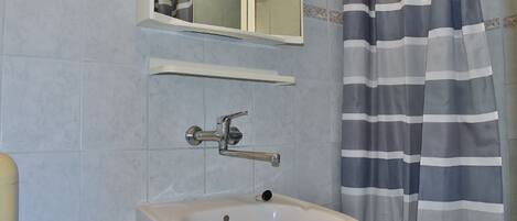 A bathroom with a sink, mirror, and striped shower curtain.