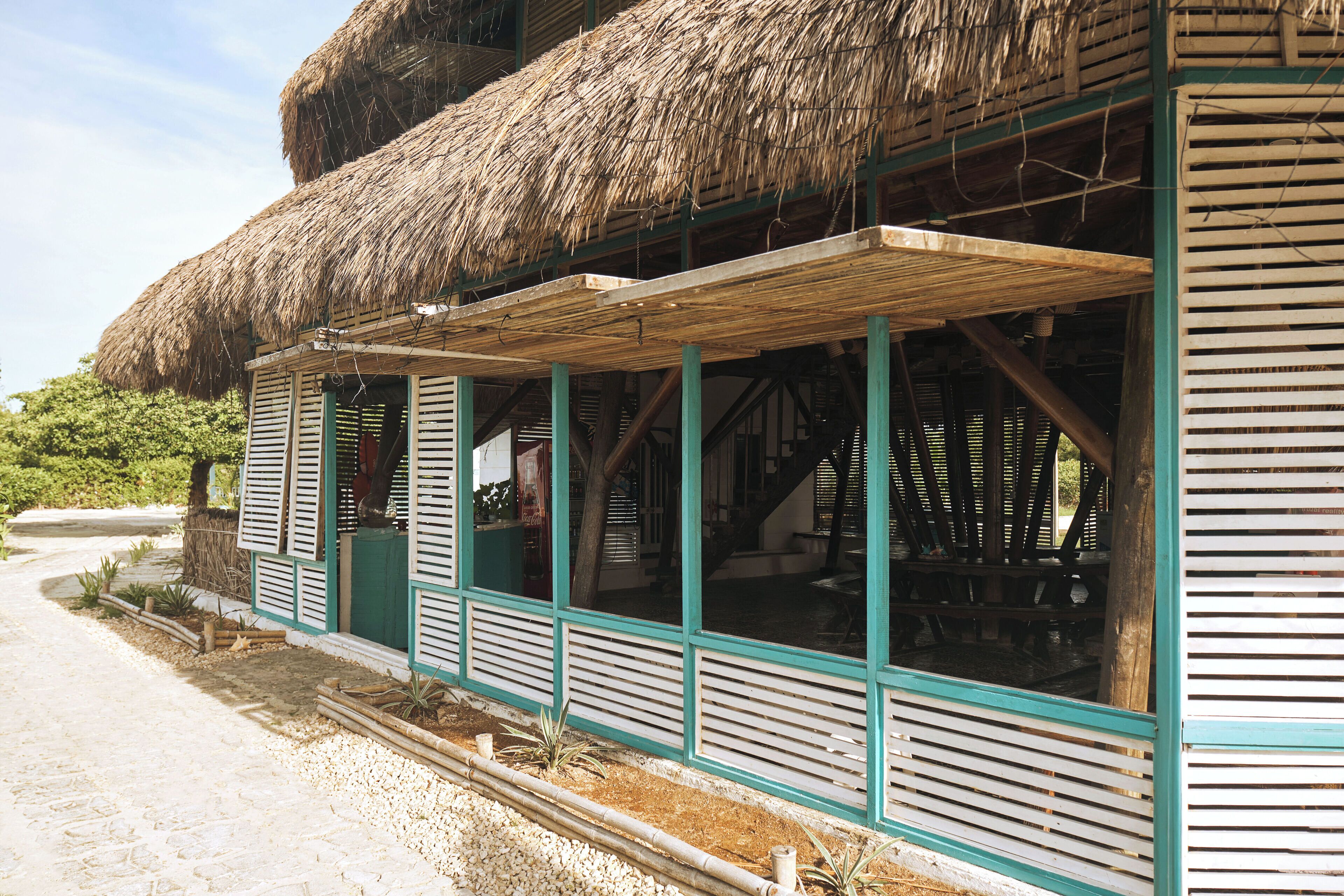 A traditional thatched-roof building with a covered veranda and a staircase leading to an upper level.