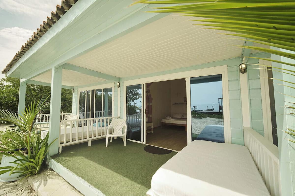 A covered outdoor area with a patio, a bed, and a view of the sea.