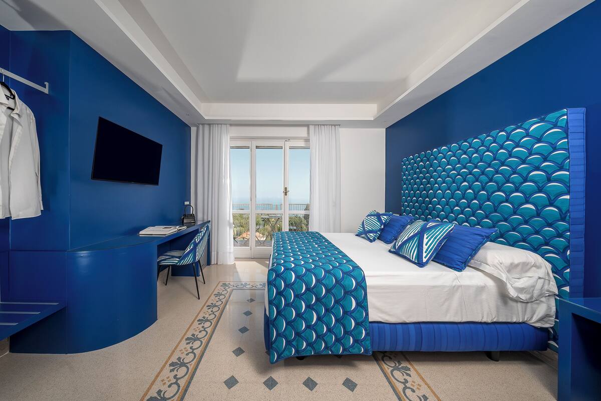 Habitación de hotel moderna con una cama grande, un escritorio y vistas al exterior.