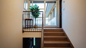 Una escalera de diseño moderno, una planta en maceta en el rellano y una lámpara en el techo.