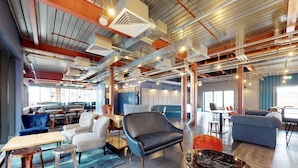 A modern lounge area with seating, tables, and exposed ductwork. - For Students Only The Bridge in Newcastle (Newcastle-upon-Tyne)