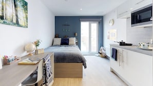 A modern bedroom with a large bed, a desk, and a view of the city through a window. - For Students Only The Bridge in Newcastle (Newcastle-upon-Tyne)