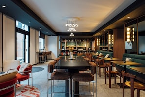 A modern restaurant with a central dining table, booths, and bar seating.