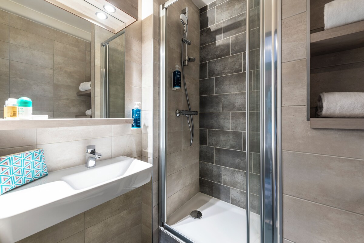 A bathroom with a shower, sink, and mirror.
