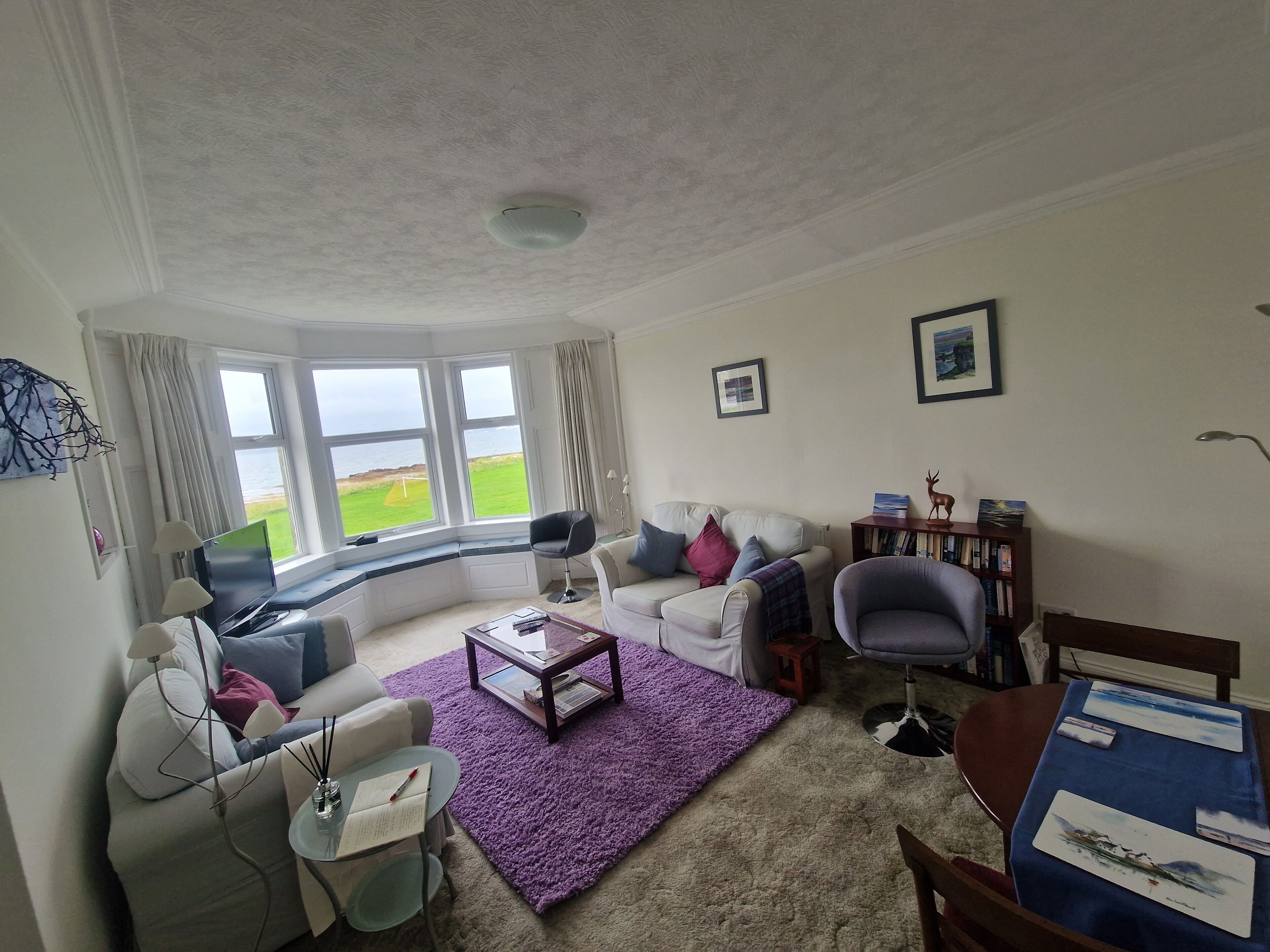 Ein Wohnzimmer mit Meerblick, inklusive Sofa, Sessel, Couchtisch und Bücherregal.