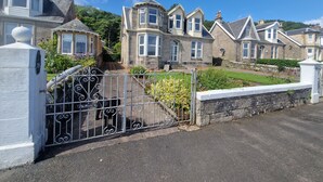 A row of stone houses with bay windows and a gated driveway. - Fairview (Isle of Cumbrae)