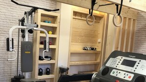 Ein Fitnessraum mit Laufband, Krafttrainingsgeräten und einer fest installierten Ringstation.