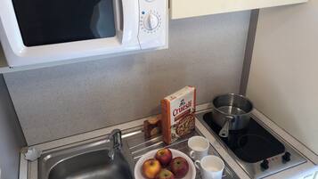 A kitchen with a microwave, sink, stove, and a plate of apples.