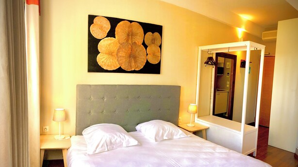Ein Hotelzimmer mit einem Bett, zwei Nachttischen, einem großen Spiegel und einem Wandbild.
